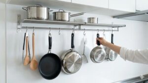 吊り下げ収納からフライパンを取り出す手元と整頓されたキッチン棚