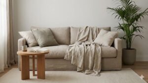 リネンソファに無造作に置かれたブランケットと本、リラックスした生活感のある部屋