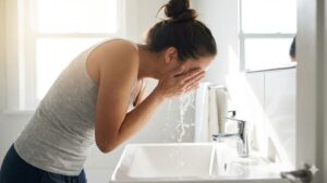 明るい洗面所で顔を洗い、水しぶきが上がっている清々しい朝のワンシーン