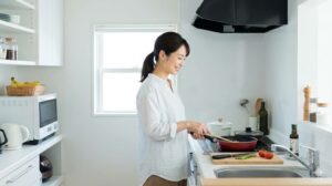 整理されたキッチンで笑顔でスムーズに料理をする女性