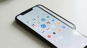 整理されたスマートフォンのホーム画面で、奥ゾーンのアプリが完璧に統一されたデザインのフォルダ(透明な円形のアイコン)に収まり、整然とグリッド上に並んでいる。フォルダによる方法の統一とシンプルさを表現したリアルな写真。